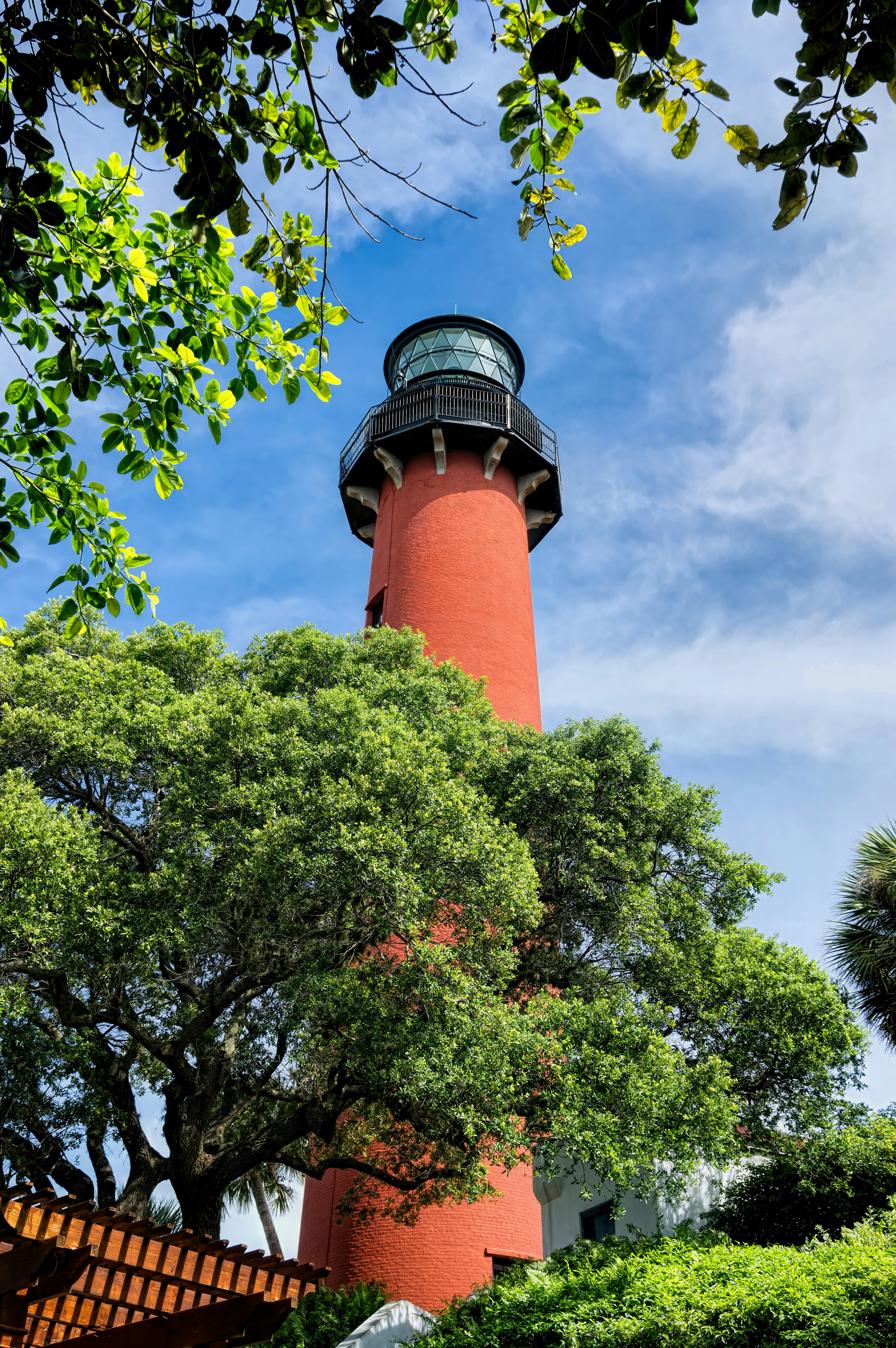 Red lighthouse viewed from bottom looking up through trees